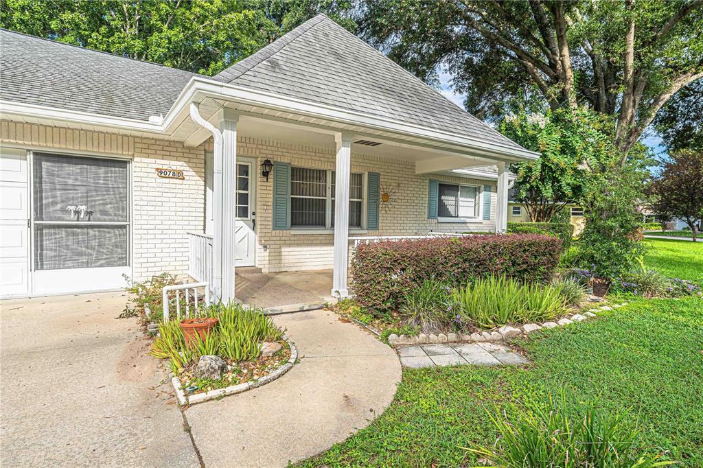 A single-story brick house with a covered front porch, a driveway, and landscaped front yard — 9078 SW 82ND TERRACE UNIT D, OCALA, FL
