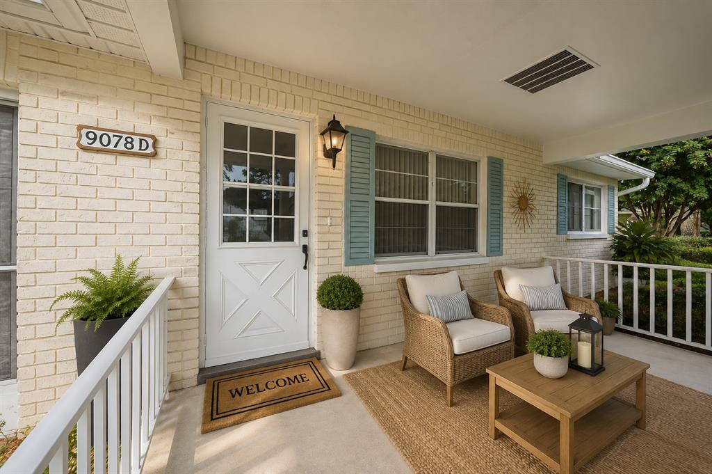 A covered front porch features a white door, wicker chairs, and a small wooden table — 9078 SW 82ND TERRACE UNIT D, OCALA, FL