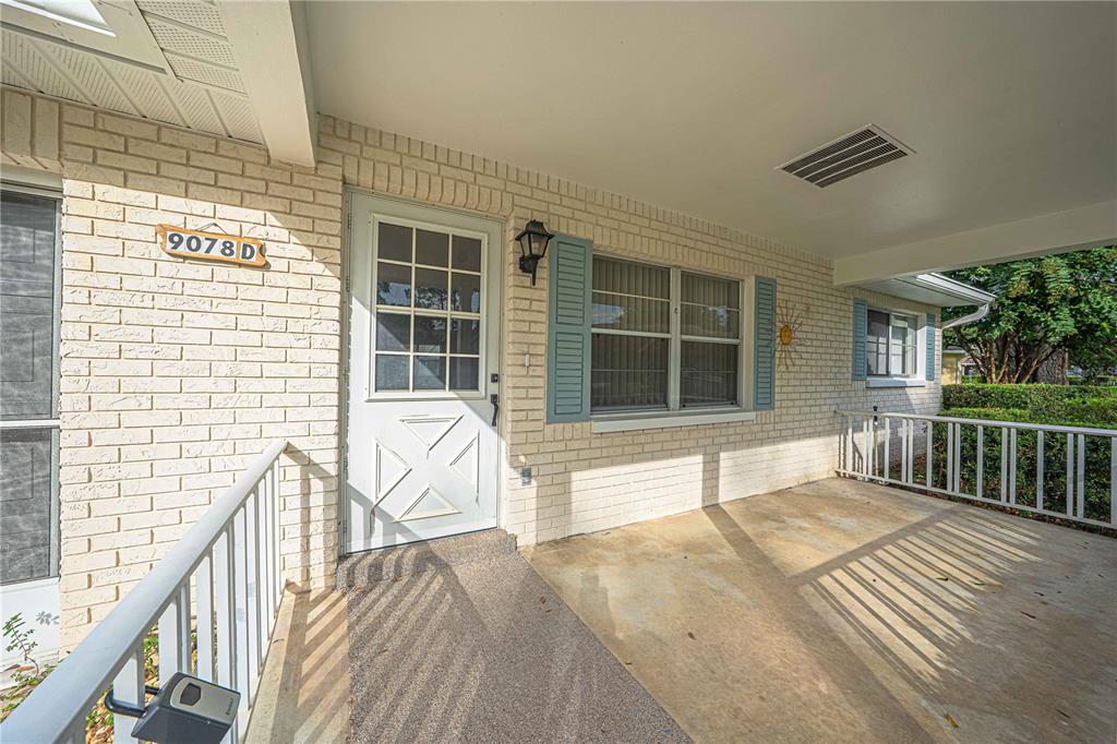 A covered porch features a white brick exterior, a white front door, and metal railings — 9078 SW 82ND TERRACE UNIT D, OCALA, FL