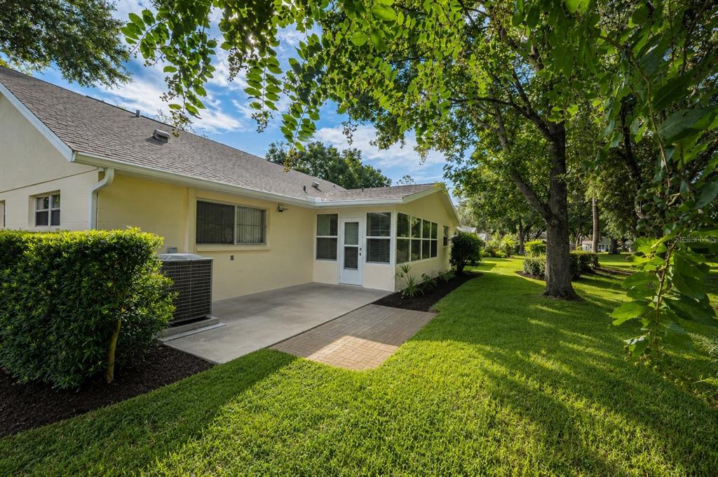 A pale yellow house exterior features a concrete patio, a sunroom, and a grassy yard — 9078 SW 82ND TERRACE UNIT D, OCALA, FL