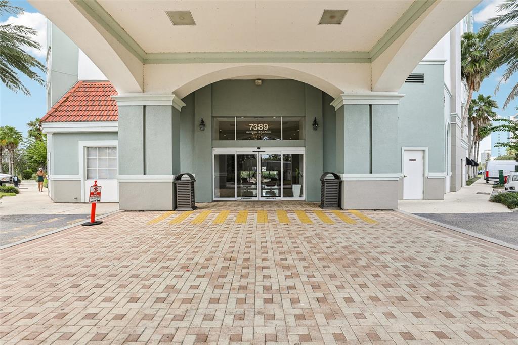 The exterior entrance of a building features a covered porte-cochère and a paved driveway — 7383 UNIVERSAL BOULEVARD UNIT 910, ORLANDO, FL