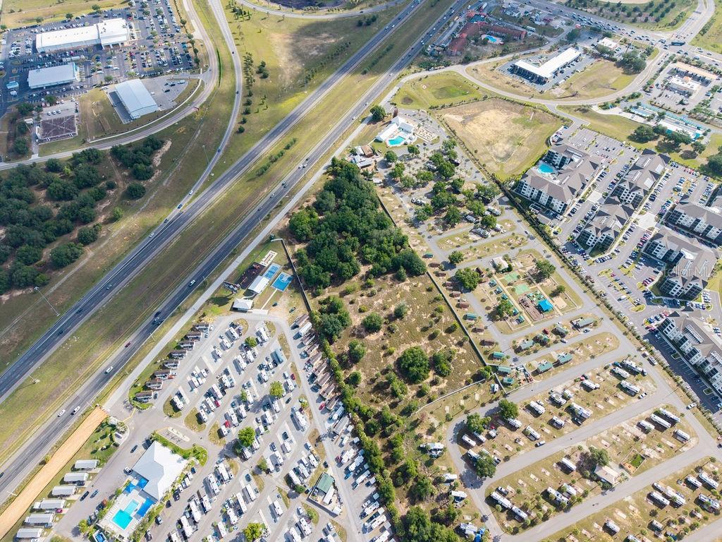 This aerial view shows a large RV park located next to a highway and apartment complex — PRIME FRONTAGE, DAVENPORT, FL