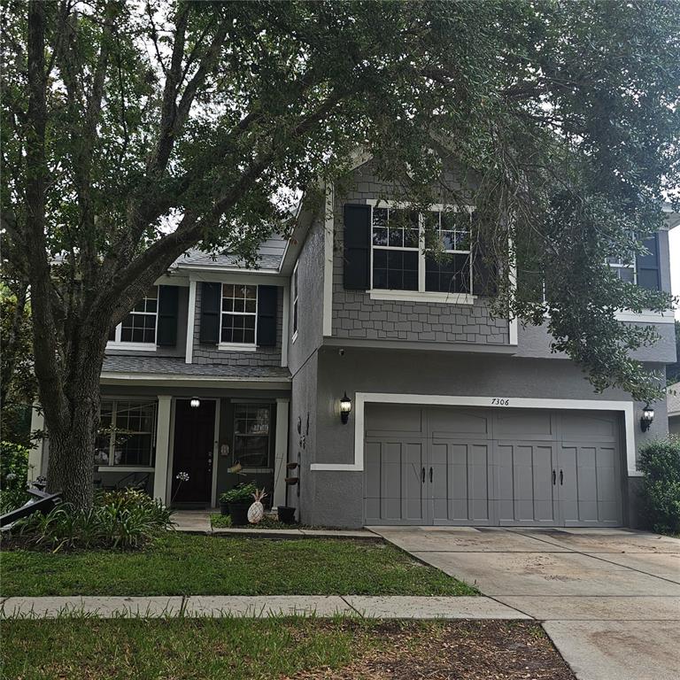 A two-story gray house with a two-car garage and a large tree in the yard — 7306 BRIDGEVIEW DRIVE, WESLEY CHAPEL, FL