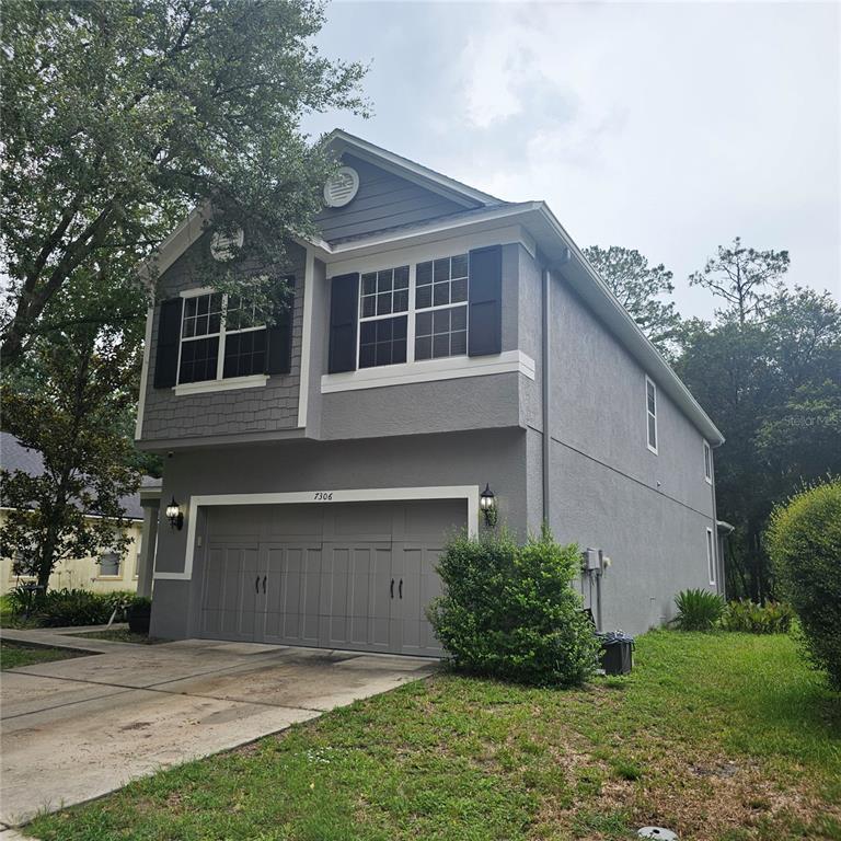 A two-story house with a gray stucco exterior, a two-car garage, and black shutters — 7306 BRIDGEVIEW DRIVE, WESLEY CHAPEL, FL