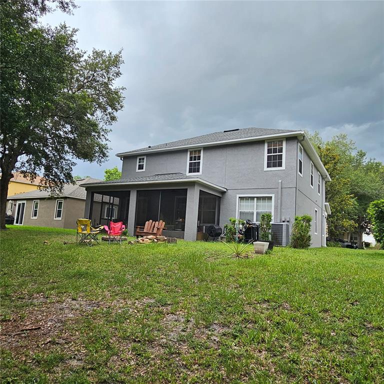 The exterior of a two-story gray house features a screened-in back porch and lawn — 7306 BRIDGEVIEW DRIVE, WESLEY CHAPEL, FL