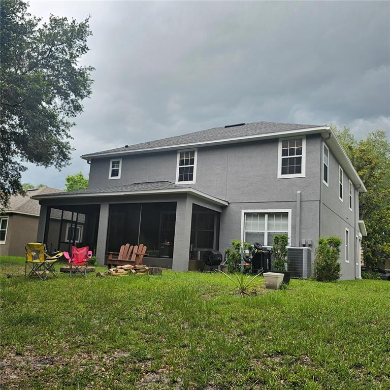 The exterior of a two-story gray house features a screened-in back porch and lawn — 7306 BRIDGEVIEW DRIVE, WESLEY CHAPEL, FL