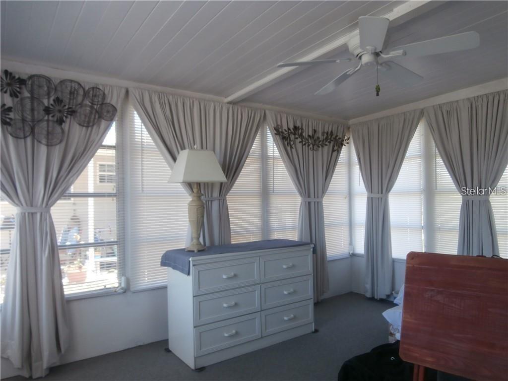 A sunroom features a white dresser, a table lamp, gray curtains, and a ceiling fan — 3204 CHANNING DRIVE, HOLIDAY, FL