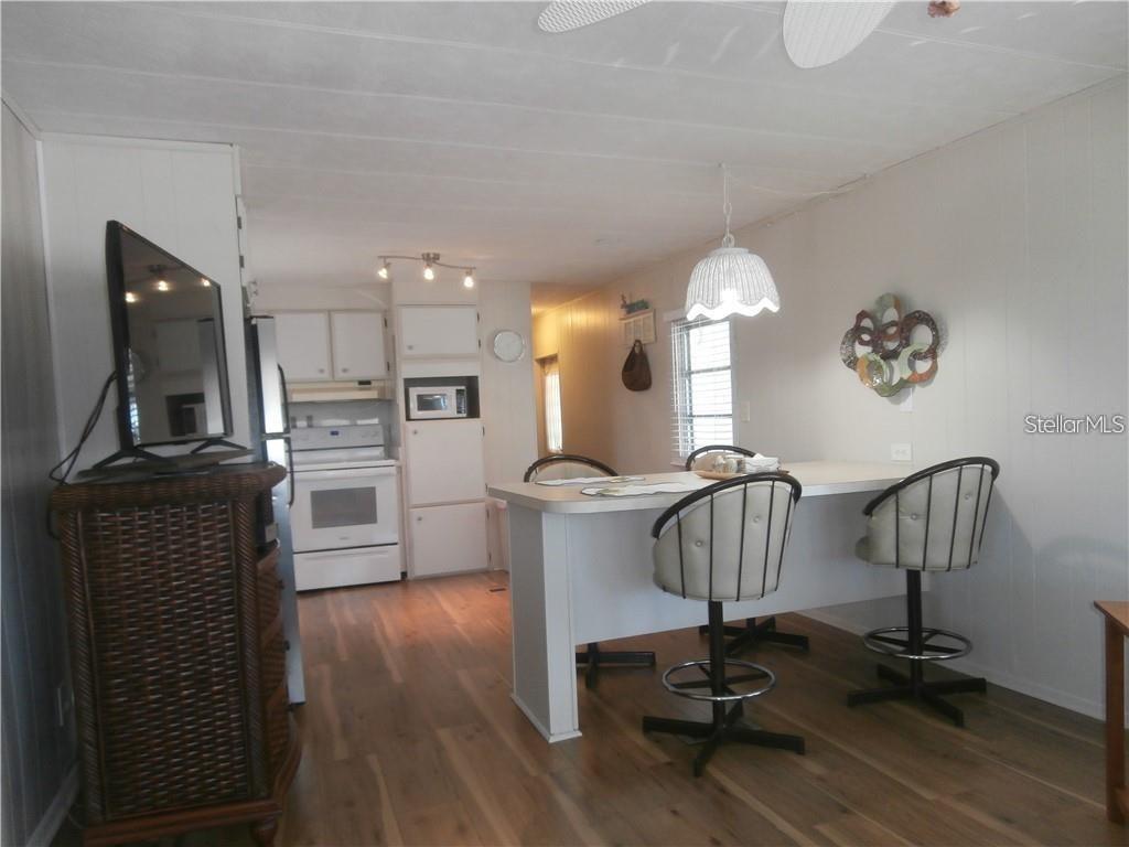 A kitchen with white cabinets and appliances features a breakfast bar with two chairs — 3204 CHANNING DRIVE, HOLIDAY, FL