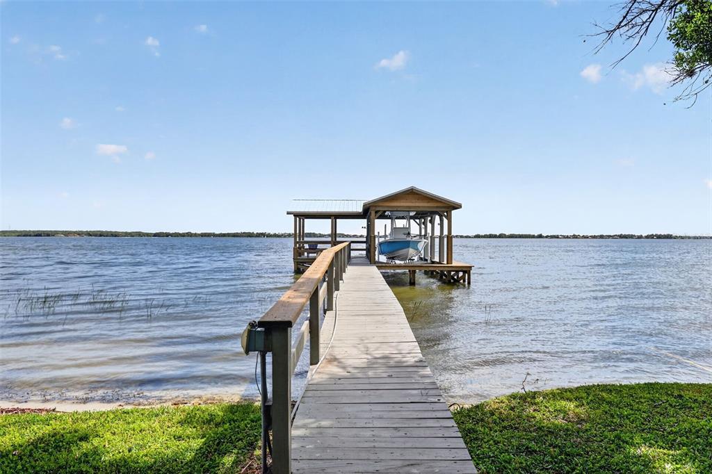 A wooden dock leads to a covered boat slip on a large lake — 1735 LAKESHORE DRIVE, MOUNT DORA, FL