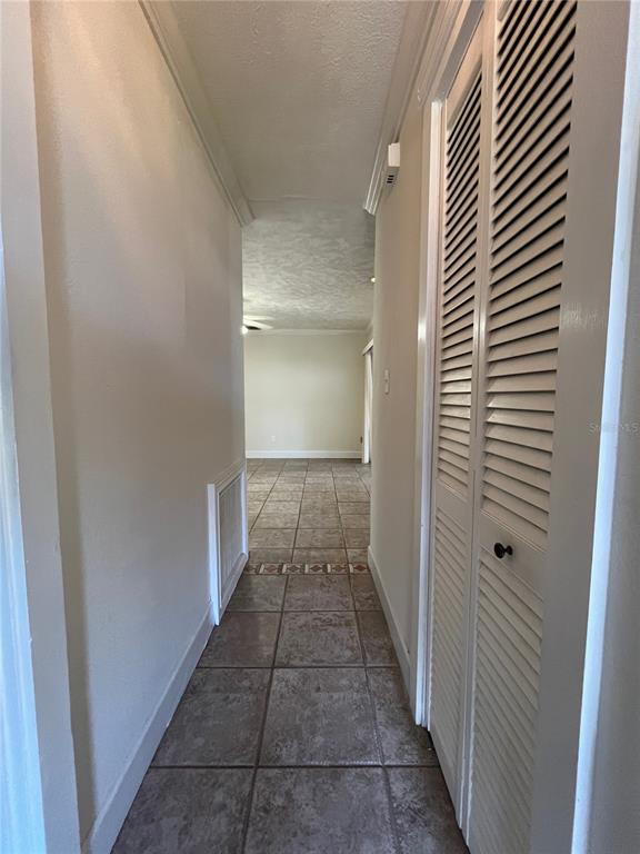 A hallway with tiled flooring leads toward an open living area with louvered closet doors — 3222 HAMMERSMITH ROAD, ORLANDO, FL