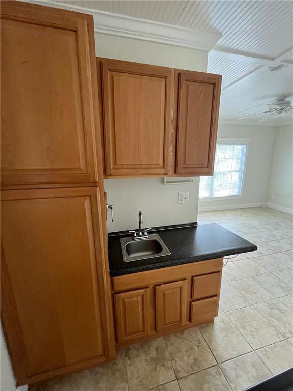 A small kitchen area features wooden cabinets, a sink, and tile flooring — 3222 HAMMERSMITH ROAD, ORLANDO, FL