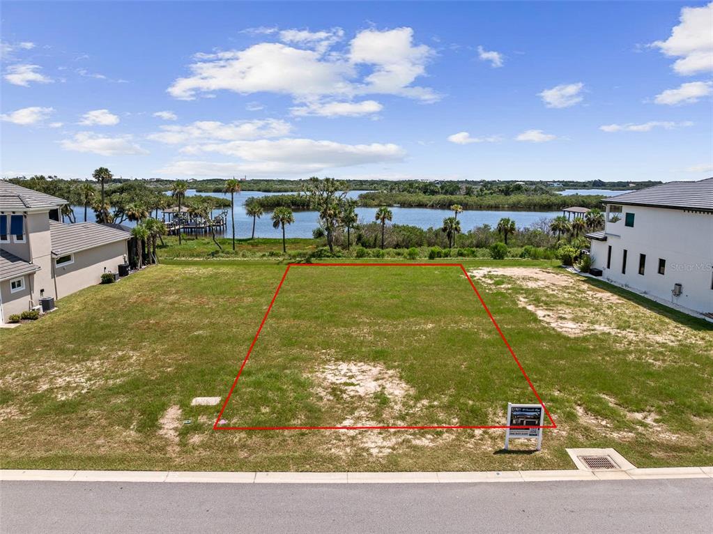 An aerial view shows a vacant waterfront lot outlined in red between two houses — 48 CORONADO ROAD, FLAGLER BEACH, FL