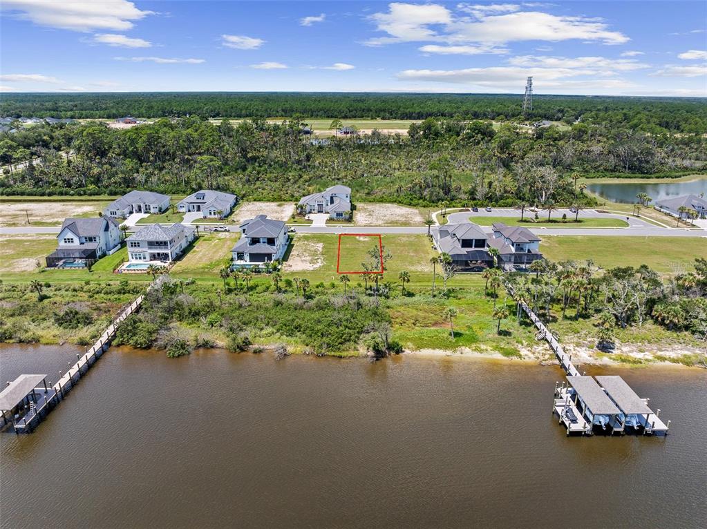 An aerial view shows a vacant waterfront lot outlined in red between two existing houses — 48 CORONADO ROAD, FLAGLER BEACH, FL