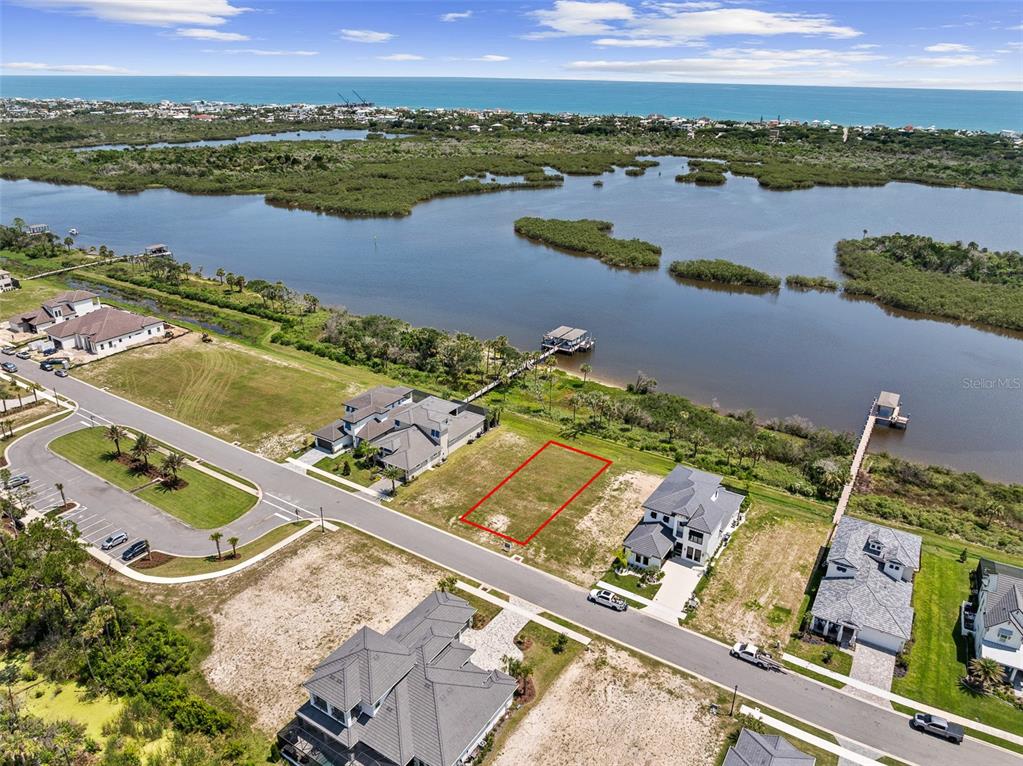 An aerial view shows a vacant rectangular lot outlined in red between two modern houses — 48 CORONADO ROAD, FLAGLER BEACH, FL