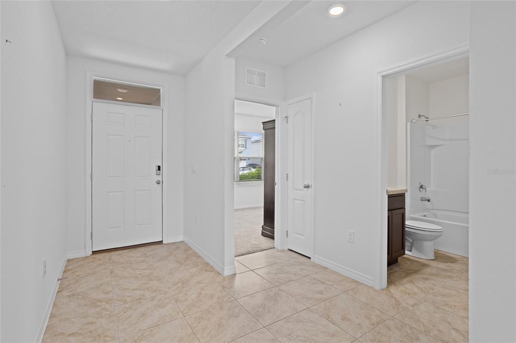 An entryway with tile flooring leads to a bedroom and a full bathroom — 2143 KALIN WAY, TAVARES, FL