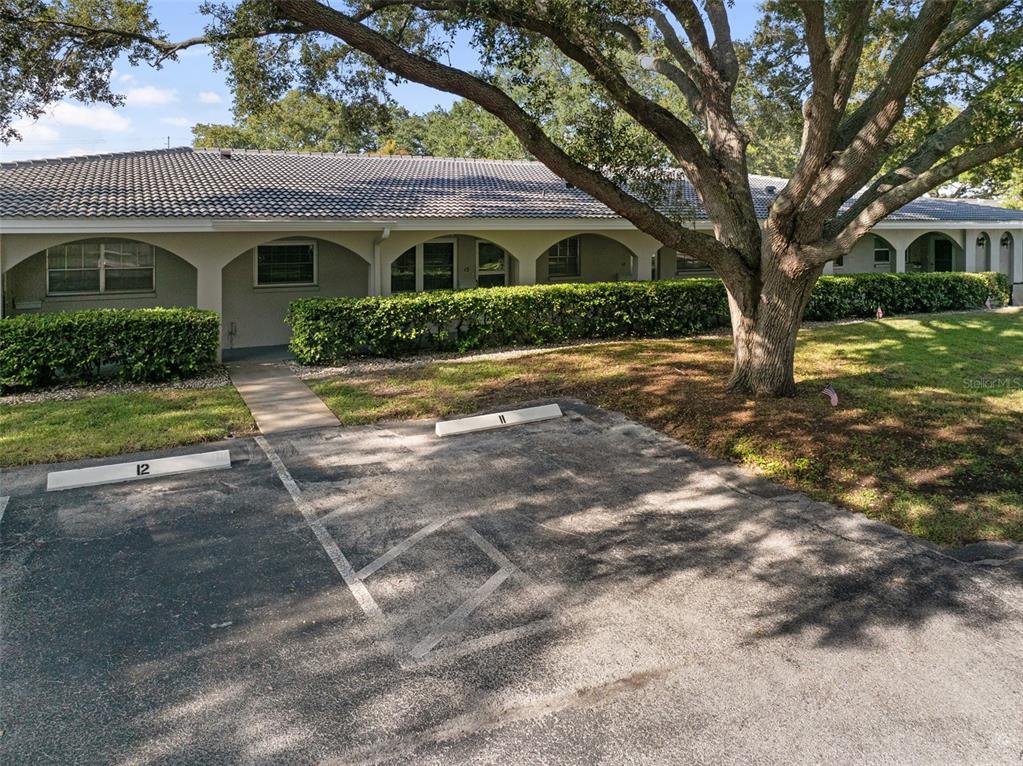 A single-story building with arched walkways, a tiled roof, and numbered parking spaces in front — 11200 102ND AVENUE UNIT 15, SEMINOLE, FL