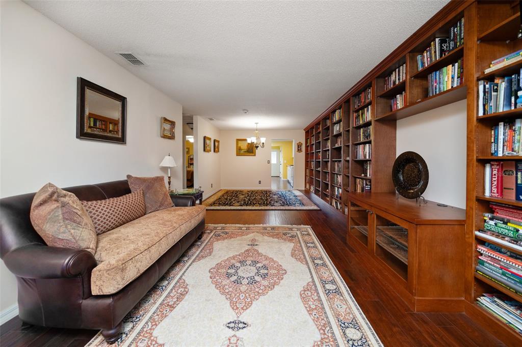 A living room features a leather sofa, two area rugs, and a large built-in wooden bookcase — 11200 102ND AVENUE UNIT 15, SEMINOLE, FL