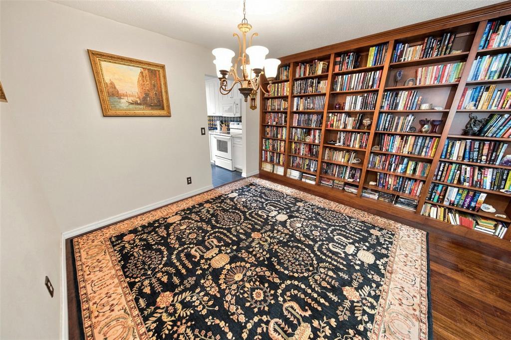 A dining room features a large patterned rug, a chandelier, and floor-to-ceiling wooden bookshelves — 11200 102ND AVENUE UNIT 15, SEMINOLE, FL