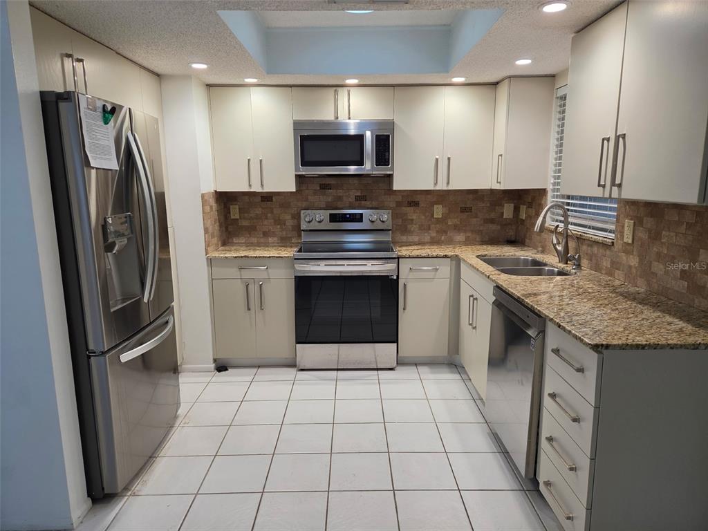 An empty room features white walls, a tiled floor, and a rolled-up piece of carpet — 749 N JEFFERSON AVENUE UNIT 749, SARASOTA, FL