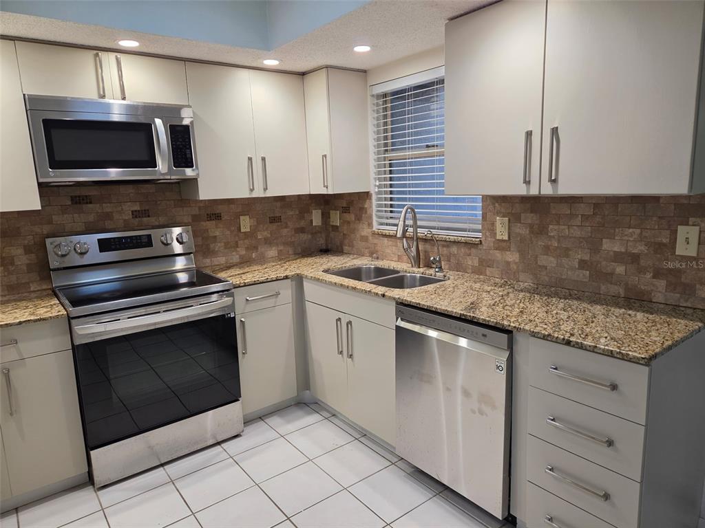 A kitchen featuring white cabinets, stainless steel appliances, granite countertops, and a tiled floor — 749 N JEFFERSON AVENUE UNIT 749, SARASOTA, FL