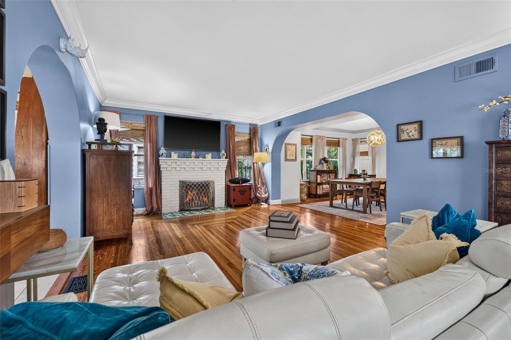 A living room with blue walls, hardwood floors, a white brick fireplace, and arched doorways — 736 30TH AVENUE N, ST PETERSBURG, FL