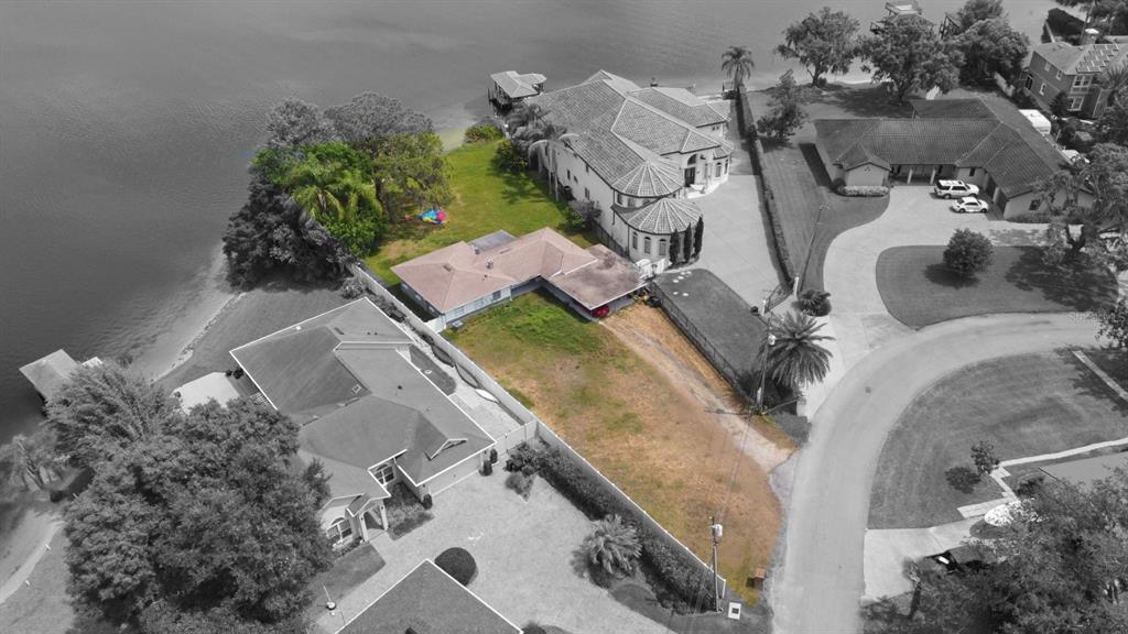 An aerial view shows a waterfront property with a house and a large vacant lot — 3045 CECELIA DRIVE, APOPKA, FL