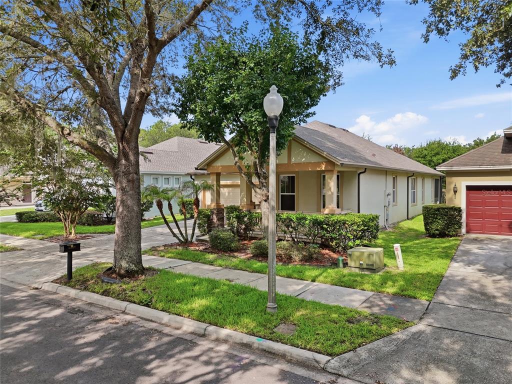 A single-story house with a front porch, a lamp post, and a red garage door — 13137 PENSHURST LANE, WINDERMERE, FL