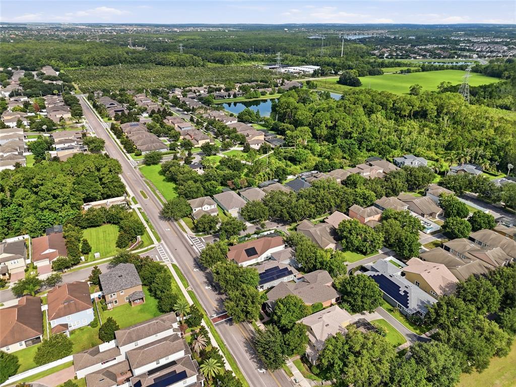 An aerial view shows a suburban neighborhood with houses, tree-lined streets, and a small lake — 13137 PENSHURST LANE, WINDERMERE, FL