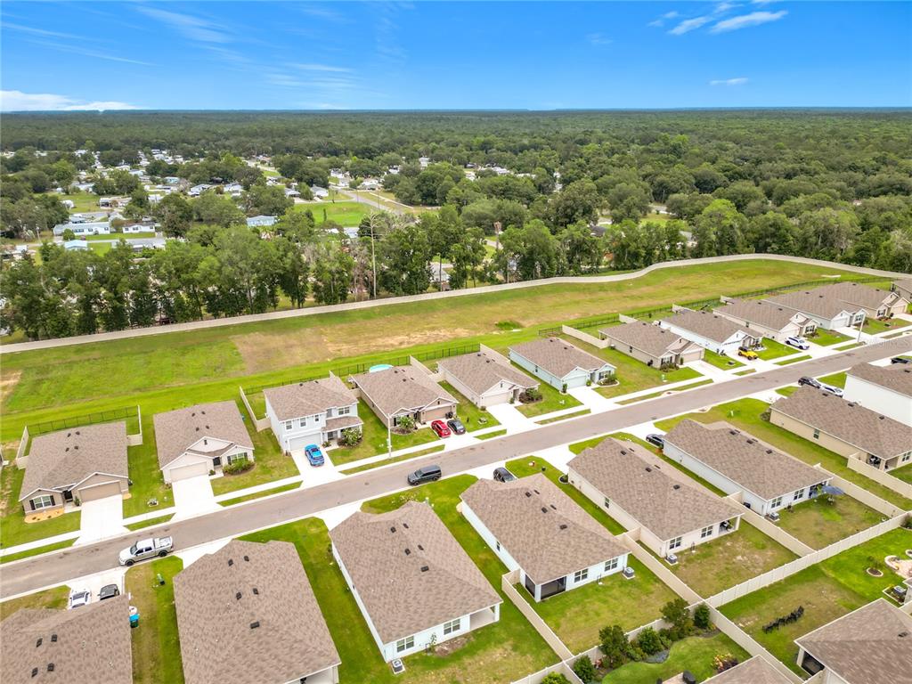 An aerial view shows a suburban neighborhood with single-family homes, paved streets, and surrounding woods — 6698 SE 3RD LOOP, OCALA, FL