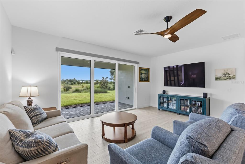 A living room features light tile floors, a ceiling fan, sliding glass doors, and furniture — 1003 WATERLINE COURT, SARASOTA, FL