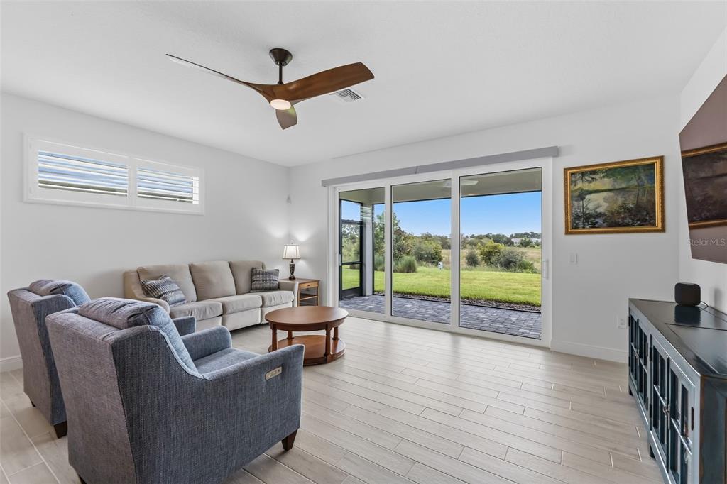 A living room features light tile floors, a ceiling fan, and sliding glass doors to outdoors — 1003 WATERLINE COURT, SARASOTA, FL