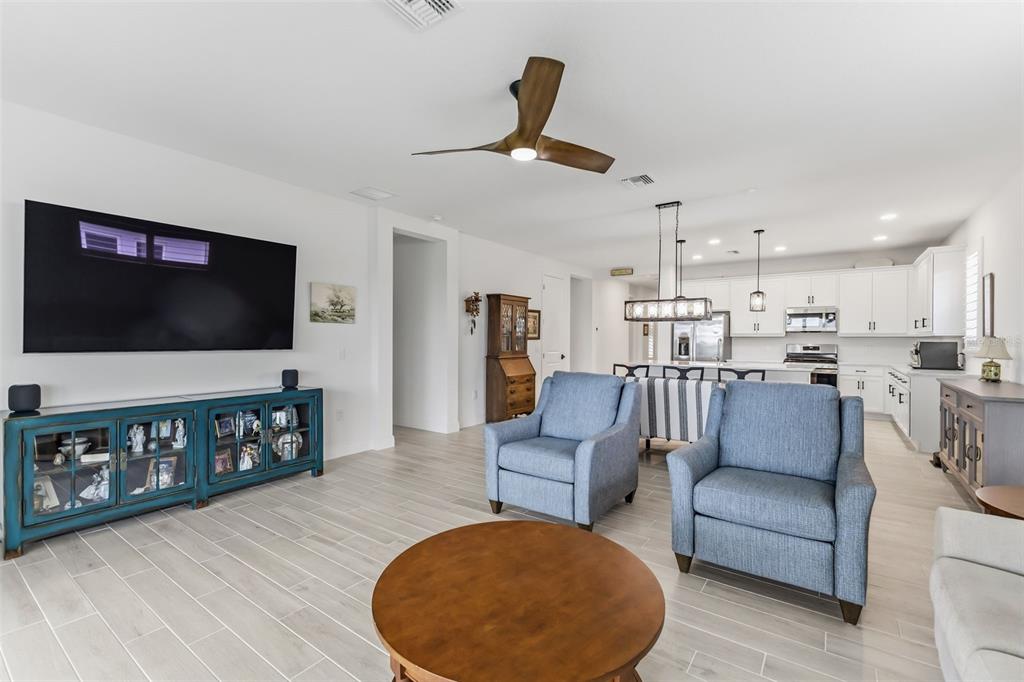 A living room with light tile floors, blue armchairs, and a kitchen in the background — 1003 WATERLINE COURT, SARASOTA, FL