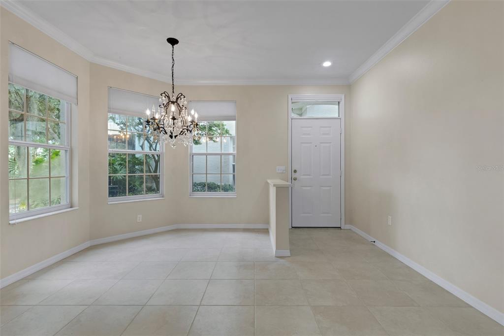A dining area features tile flooring, a crystal chandelier, and a white front door — 684 GRASSLANDS VILLAGE CIRCLE, LAKELAND, FL