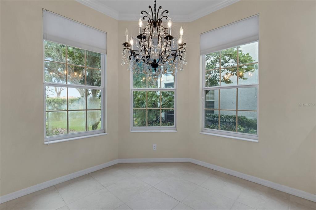 A dining room with tile flooring, a crystal chandelier, and a half-wall near the entrance — 684 GRASSLANDS VILLAGE CIRCLE, LAKELAND, FL