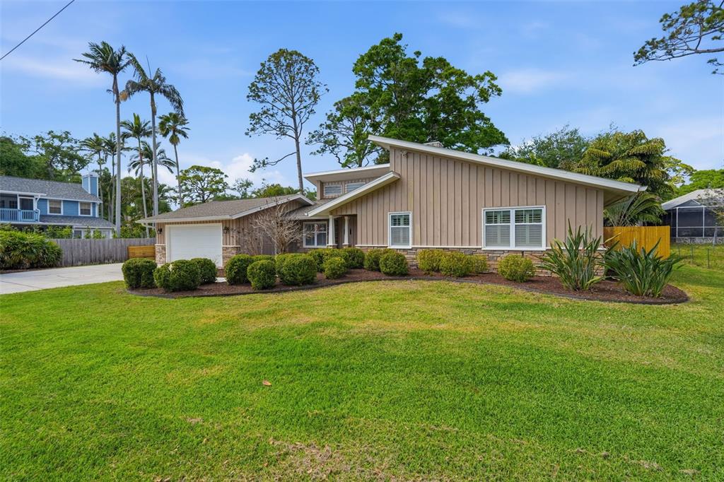 A single-story house with vertical tan siding, a stone base, and a two-car garage — 13917 76TH TERRACE, SEMINOLE, FL
