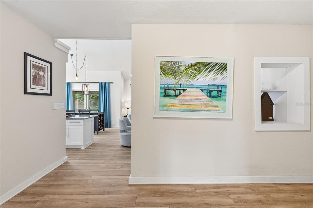 A view through an opening into a kitchen and living area with wood-look flooring — 13917 76TH TERRACE, SEMINOLE, FL