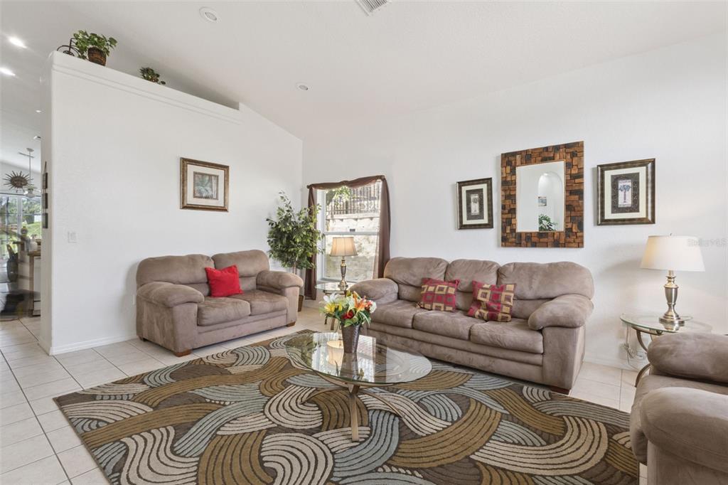 A living room features beige sofas, a patterned area rug, and a glass coffee table — 121 VINE DRIVE, DAVENPORT, FL