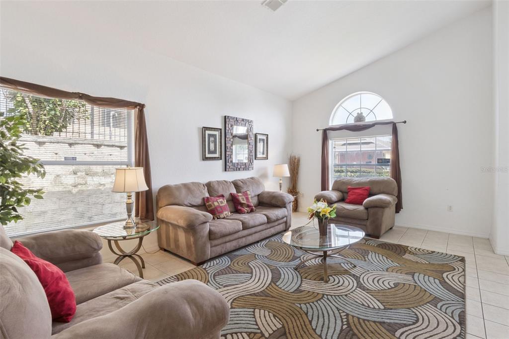 A living room features beige sofas, a patterned area rug, and an arched window — 121 VINE DRIVE, DAVENPORT, FL