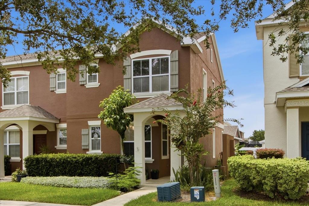 A two-story brown townhouse with a covered front porch and green landscaping — 7430 BENTONSHIRE AVENUE, WINDERMERE, FL