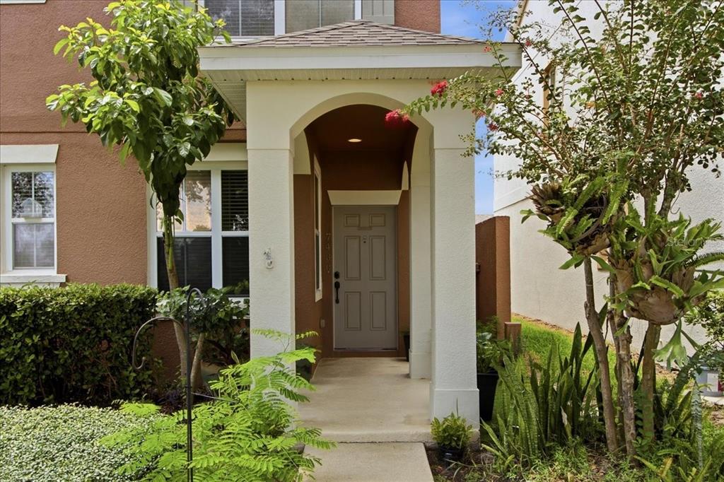 A covered entryway with a gray front door and white columns in front of a house — 7430 BENTONSHIRE AVENUE, WINDERMERE, FL