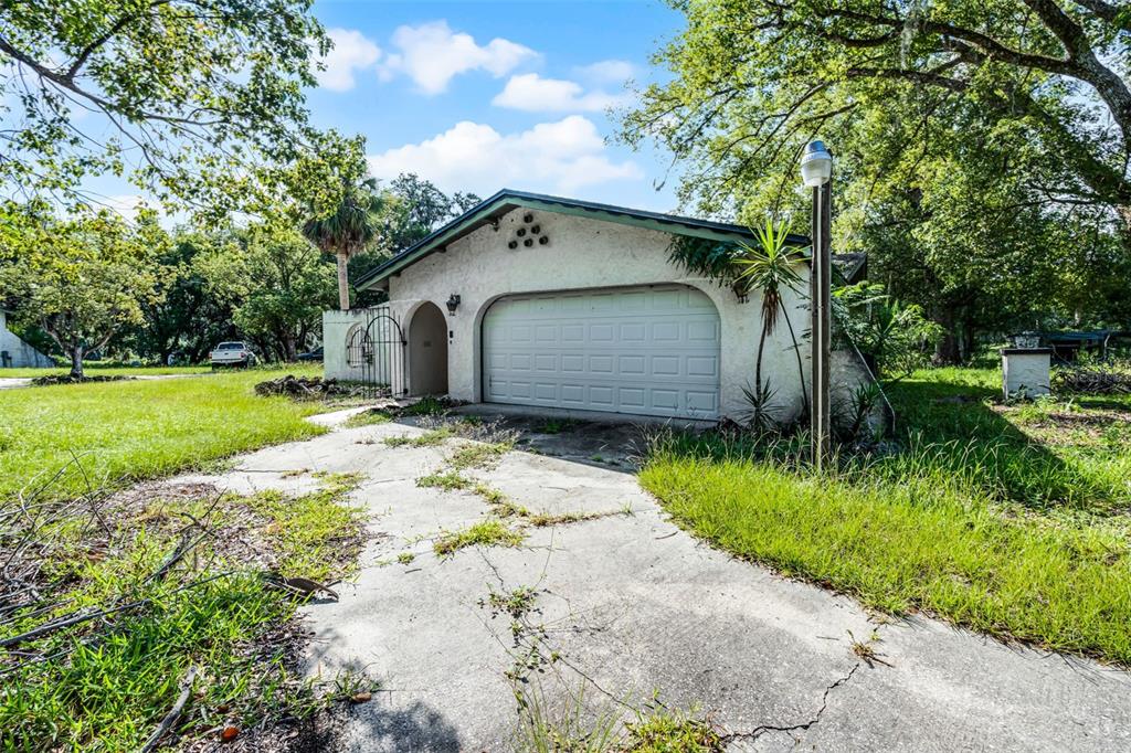 A detached garage with a white stucco exterior and a concrete driveway sits among trees — 7625 CLARCONA OCOEE ROAD, ORLANDO, FL