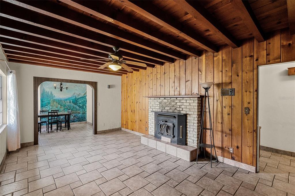 A living room features wood-paneled walls, exposed ceiling beams, a brick fireplace, and tiled floors — 7625 CLARCONA OCOEE ROAD, ORLANDO, FL