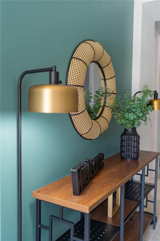A console table with a welcome sign and plant sits below a round cane mirror — 8981 AMELIA DOWNS TRAIL, KISSIMMEE, FL