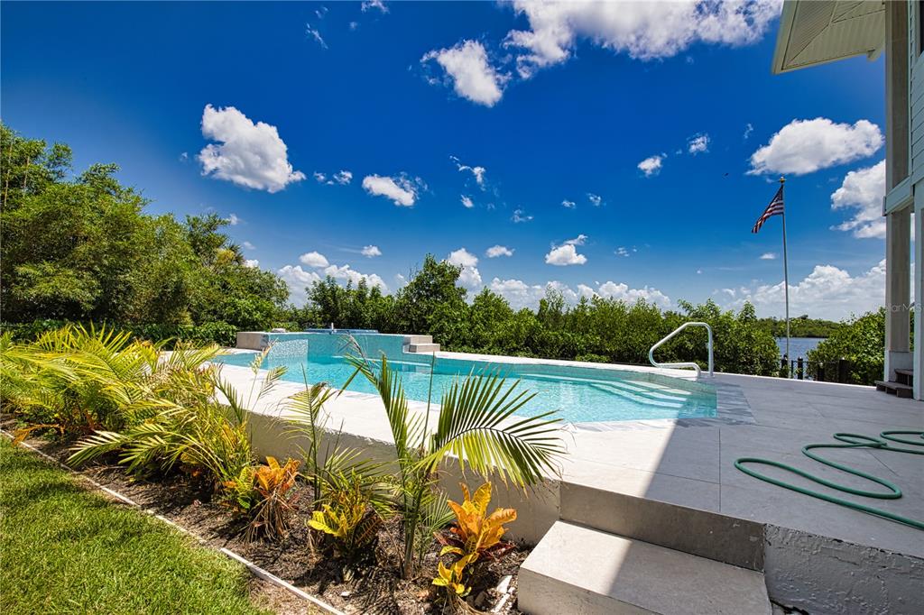 An elevated swimming pool overlooks a lush green landscape under a bright blue sky — 13064 VIA FLAVIA, PLACIDA, FL