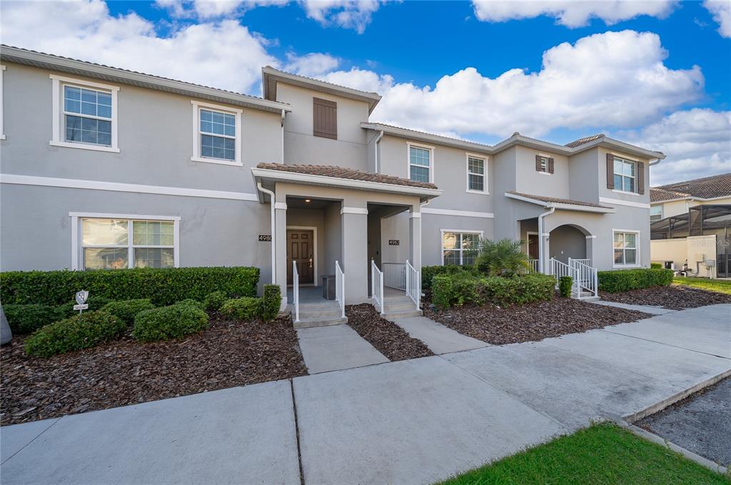 A two-story townhouse exterior with gray stucco walls, multiple windows, and two covered entryways — 4982 WINDERMERE AVENUE, KISSIMMEE, FL
