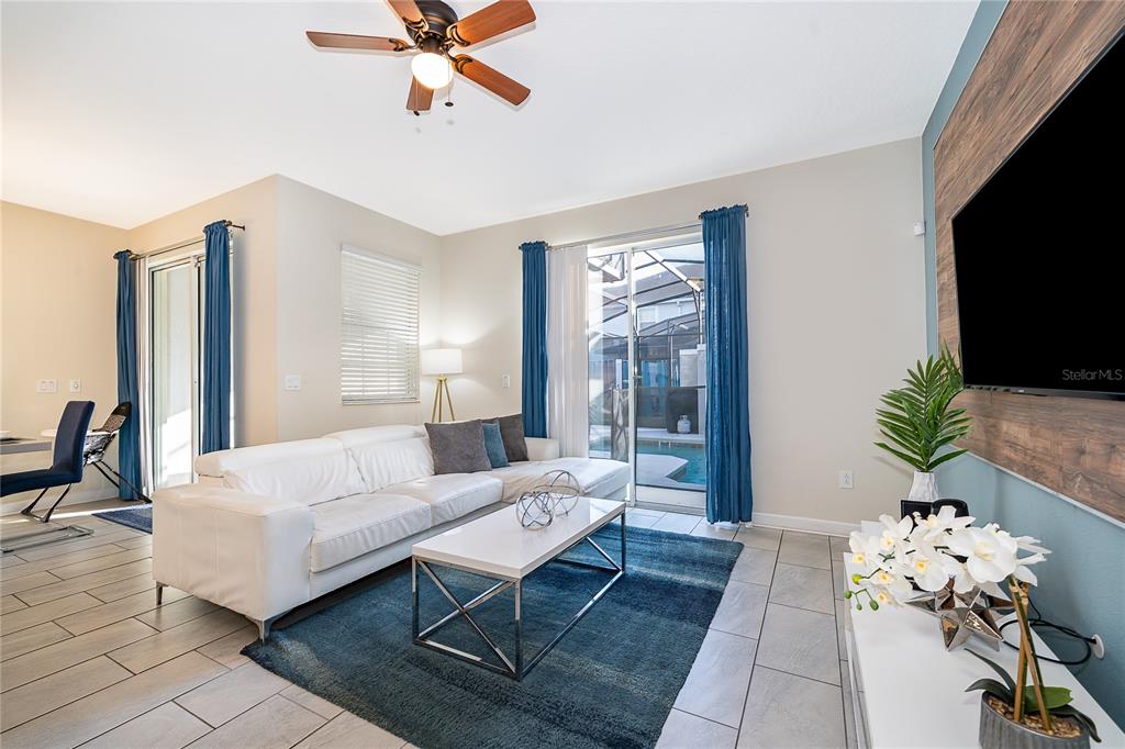 A living room features a white sectional sofa, a blue area rug, and sliding glass doors — 4982 WINDERMERE AVENUE, KISSIMMEE, FL
