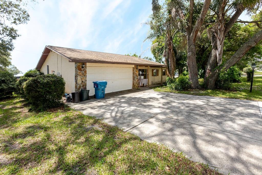 A single-story house exterior features a two-car garage, stone accents, and a concrete driveway — 1042 TRYON CIRCLE, SPRING HILL, FL