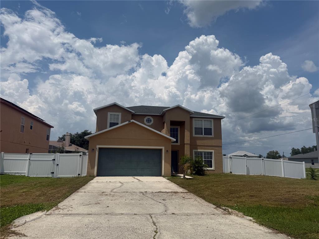 A two-story tan house with a two-car garage and a white vinyl fence — 401 MALLARD WAY, KISSIMMEE, FL