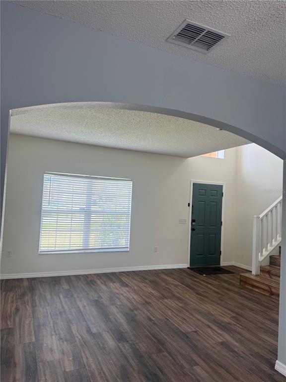 A living room features wood-look flooring, a large arched entryway, and a dark green front door — 401 MALLARD WAY, KISSIMMEE, FL