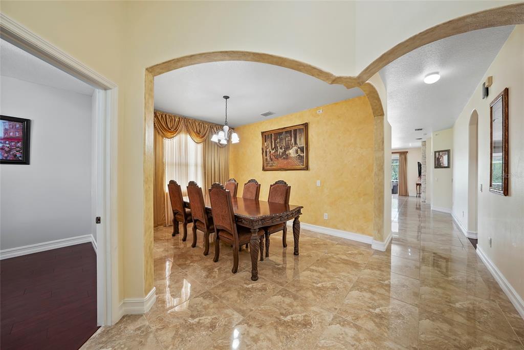 A formal dining room with a wooden table, chairs, and yellow textured walls — 3817 LANGDRUM DRIVE, WESLEY CHAPEL, FL